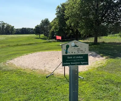 Par 3 hole sign in front of a sand green with red flag at Shell Creek Valley Golf Course in Newman Grove, Nebraska