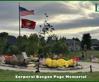 Corporal Daegan Page Memorial with flags and yellow mums at Lake Ridge Golf Course in Plattsmouth, Nebraska