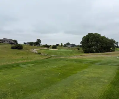 Tee view down a fairway to a green with hillside homes at The Greens At Prairie Hills in Pleasanton, Nebraska