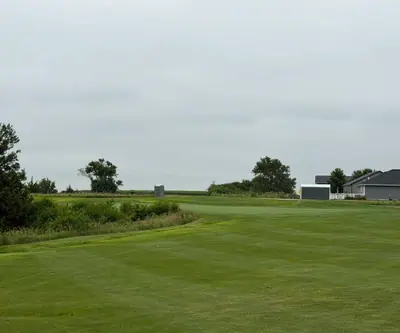 Fairway leading to a green beside homes under an overcast sky at The Greens At Prairie Hills in Pleasanton, Nebraska