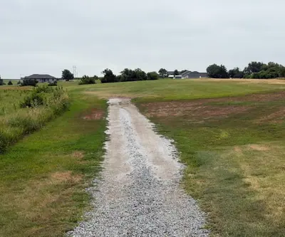Gravel cart path running between grassy fairways toward homes at The Greens At Prairie Hills in Pleasanton, Nebraska