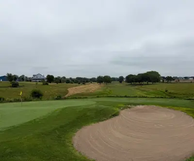 Green with a yellow flag beside a large raked bunker at The Greens At Prairie Hills in Pleasanton, Nebraska