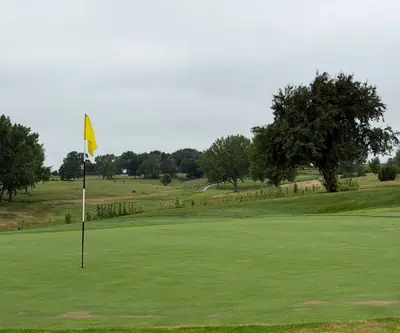 Green with yellow flagstick overlooking rolling fairways and trees at The Greens At Prairie Hills in Pleasanton, Nebraska