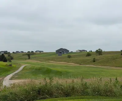 Cart path winding through rolling fairways with homes on the ridge at The Greens At Prairie Hills in Pleasanton, Nebraska