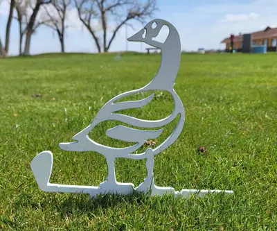 White metal goose cutout standing on a golf-club base in the grass at Riverview Golf Course in Scottsbluff, Nebraska