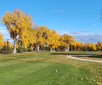 Tee box framed by golden fall cottonwoods and a cart path at Riverview Golf Course in Scottsbluff, Nebraska