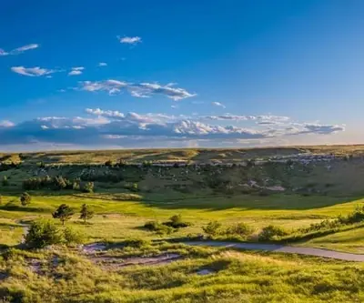 Panoramic view of sunlit rolling hills and a winding cart path at Hillside Golf Course in Sidney, Nebraska