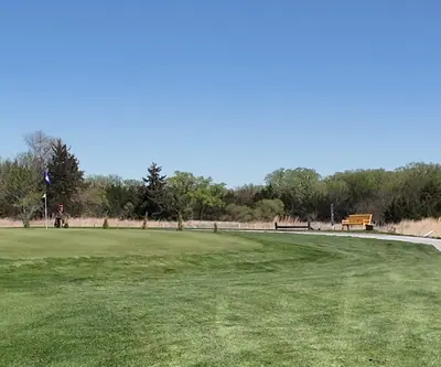 Green with a flagstick, curving cart path and yellow bench at St. Paul Country Club in St. Paul, Nebraska