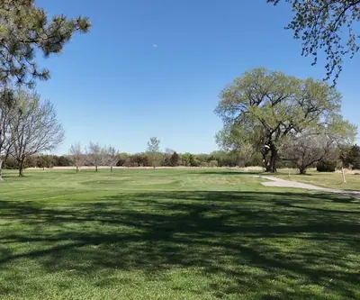 Tee view down a spring fairway with a curving cart path and large shade tree at St. Paul Country Club in St. Paul, Nebraska